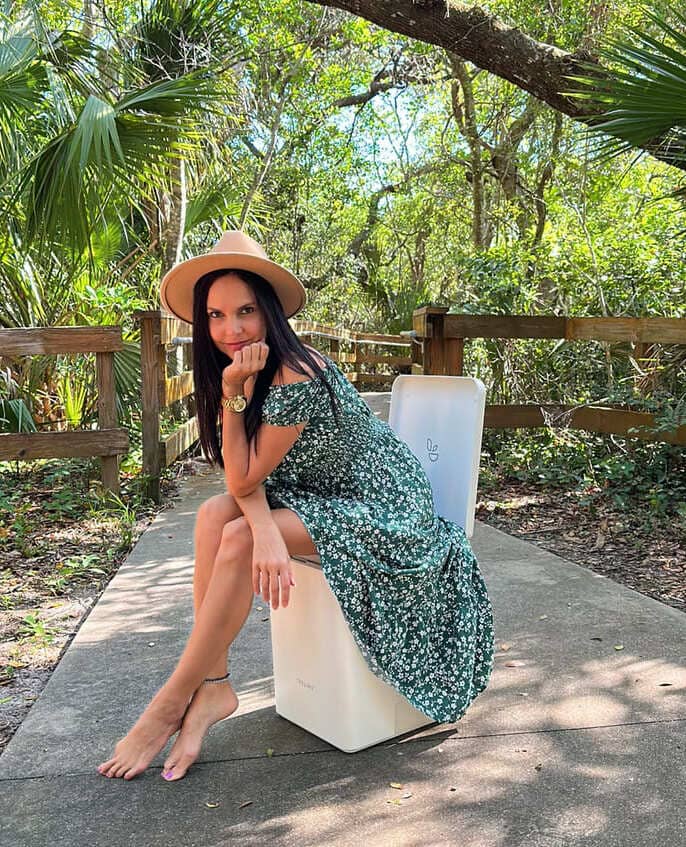 Frau sitzt auf Trelino Evo L in Weiß umgeben von einer dschungelligen Landschaft.