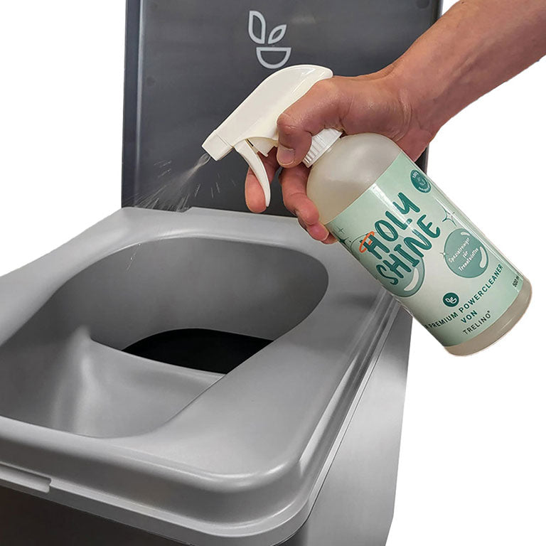 Hand sprüht Holy Shine Flüssigreiniger in anthrazitfarbene Trelino® Trenntoilette.