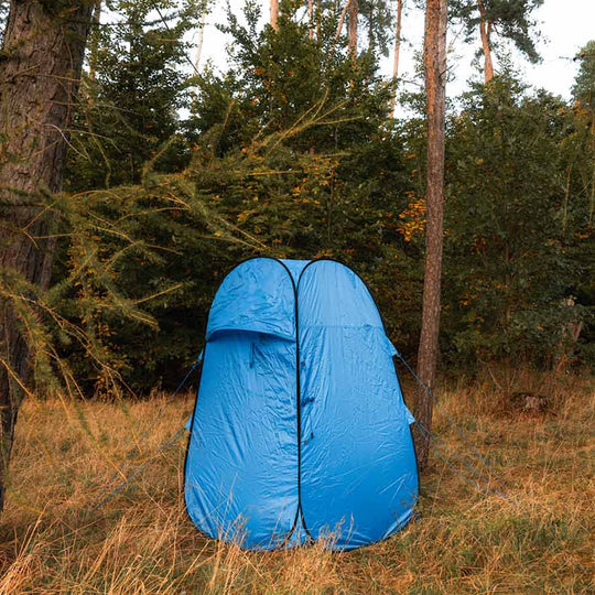 Blaues Popup-Toilettenzelt aus wasserabweisendem Material im Wald auf Wiese.