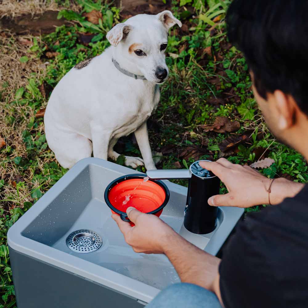 Anthrazitfarbenes mobiles Waschbecken mit integriertem Wasserhahn und Faltschüssel beim Outdoor-Einsatz.