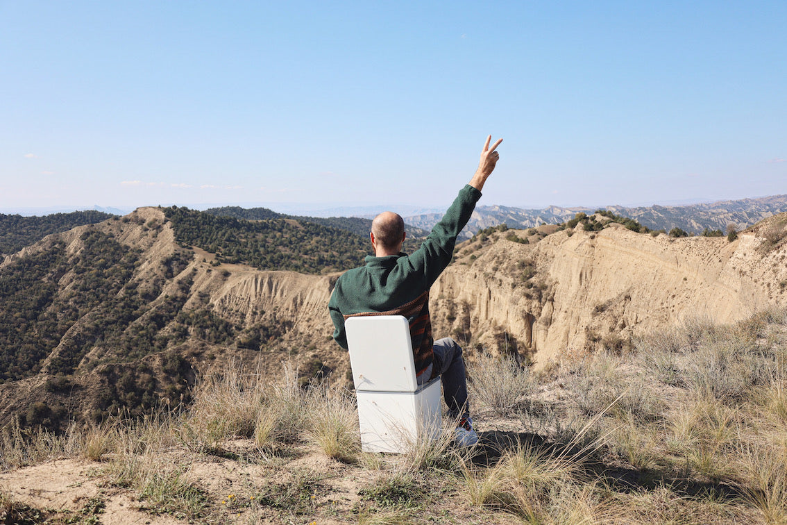 man sitting on composting toilet with hills view